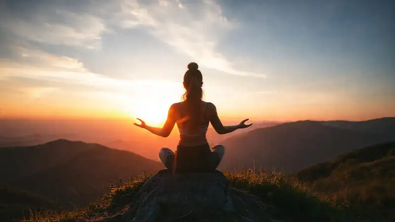 Mujer meditando en cima con luz suave